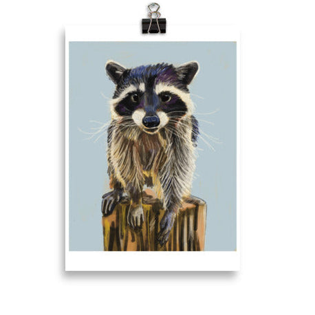 Illustration of a raccoon on a log with a light blue background, hanging on a white wall.